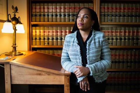 Judge Ketanji Brown Jackson leaning against a podium in front of a bookcase